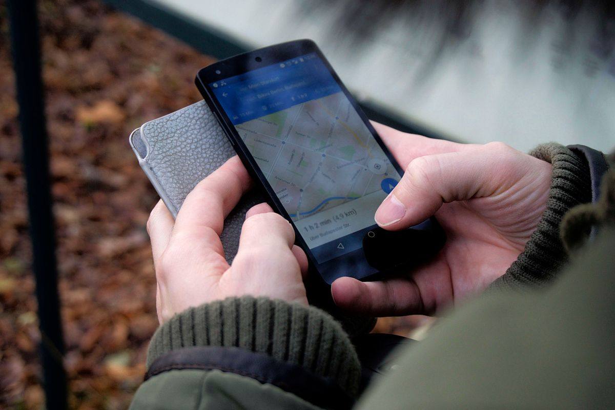 Hands using a smartphone map while searching for directions.